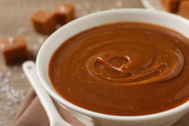 Yummy salted caramel in bowl on table, closeup