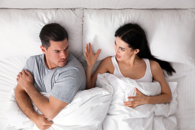 Photo of Couple quarreling in bed at home, top view. Relationship problems