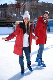 Lovely couple spending time together at outdoor ice skating rink