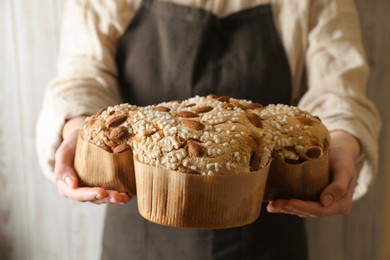 Photo of Woman with delicious Italian Easter dove cake (traditional Colomba di Pasqua) near white wooden wall, closeup