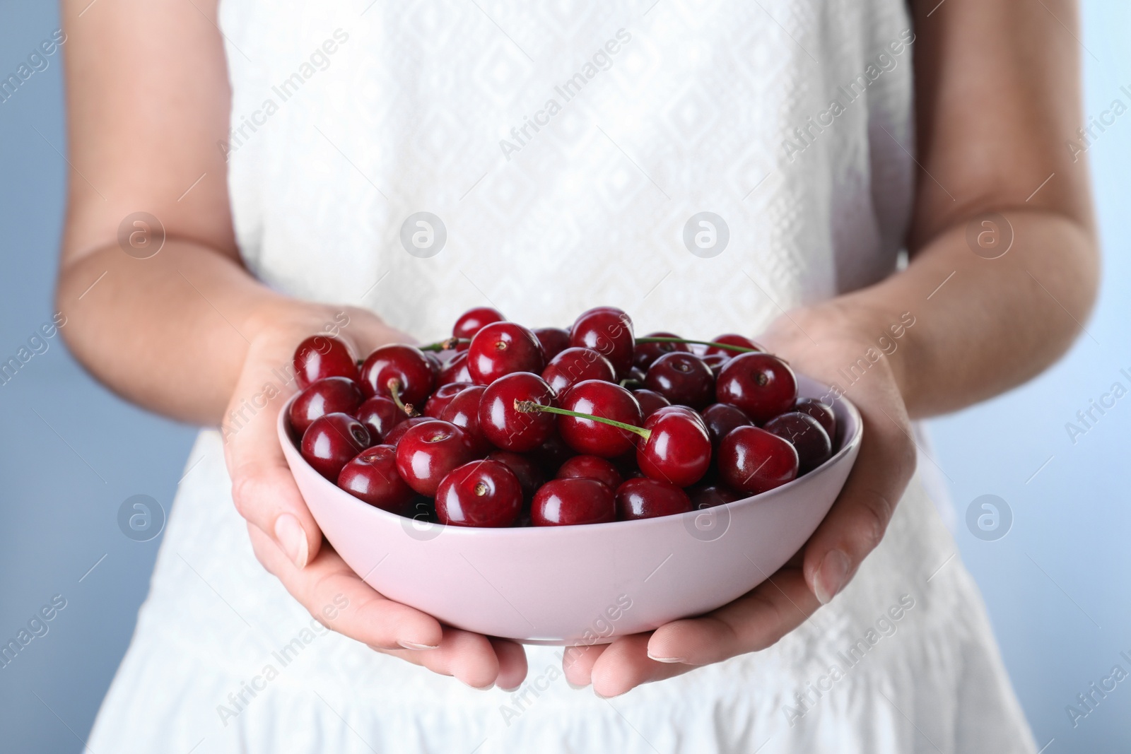 Photo of Woman holding bowl with ripe cherries, closeup