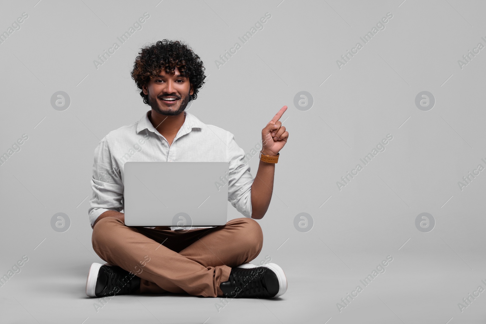 Photo of Smiling man with laptop on light grey background, space for text