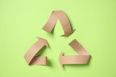 Recycling symbol cut out of paper on green background, top view