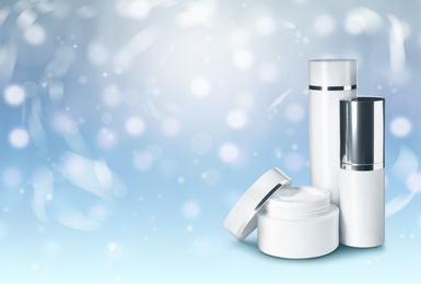 Image of Different cosmetic products on light blue background with bokeh effect, space for text. Winter skin care