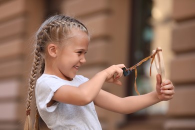 Photo of Little girl playing with slingshot on city street