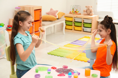 Photo of Happy girls playing with slime in room