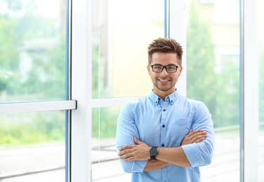 Portrait of handsome young man with glasses near window