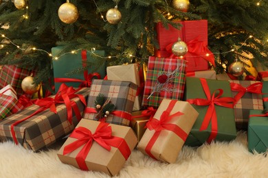 Photo of Many gift boxes under beautiful Christmas tree in room
