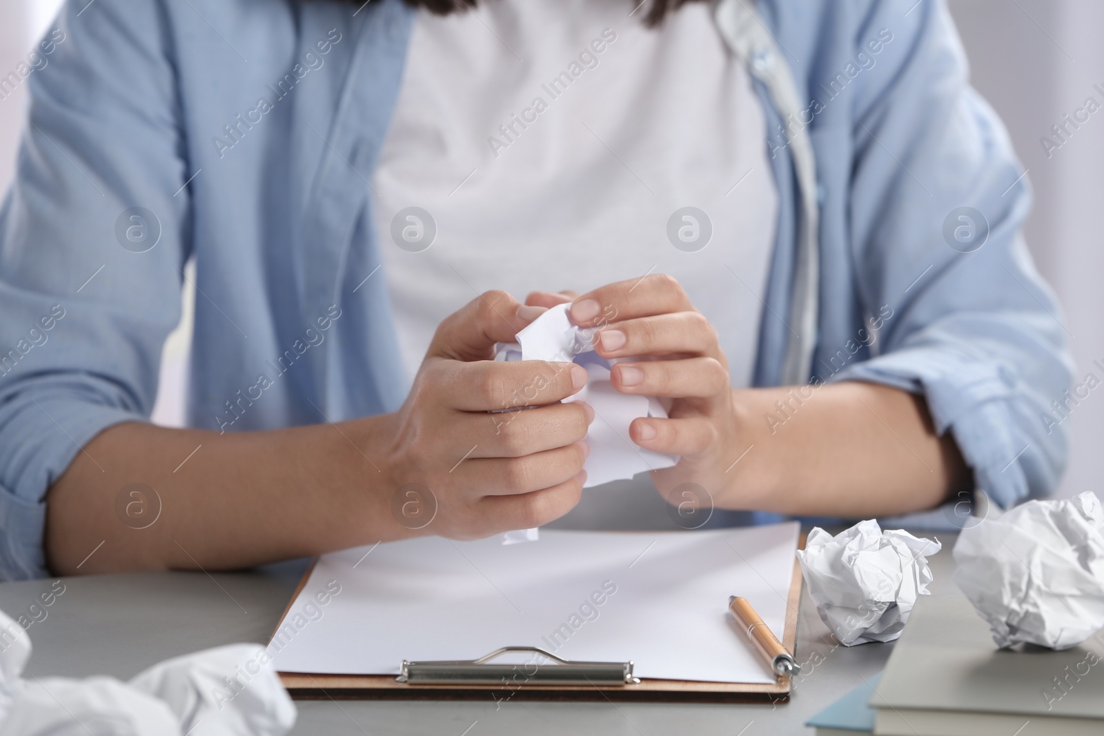 Photo of Woman crumpling paper at table, closeup. Generating idea