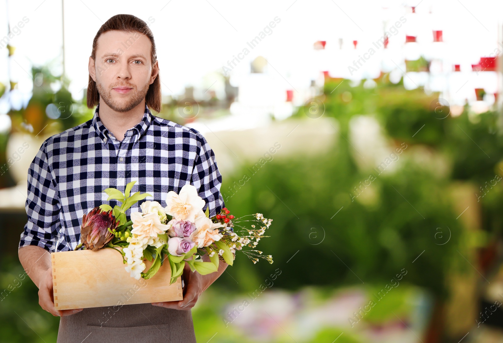 Image of Florist holding basket with flowers in shop. Space for text 