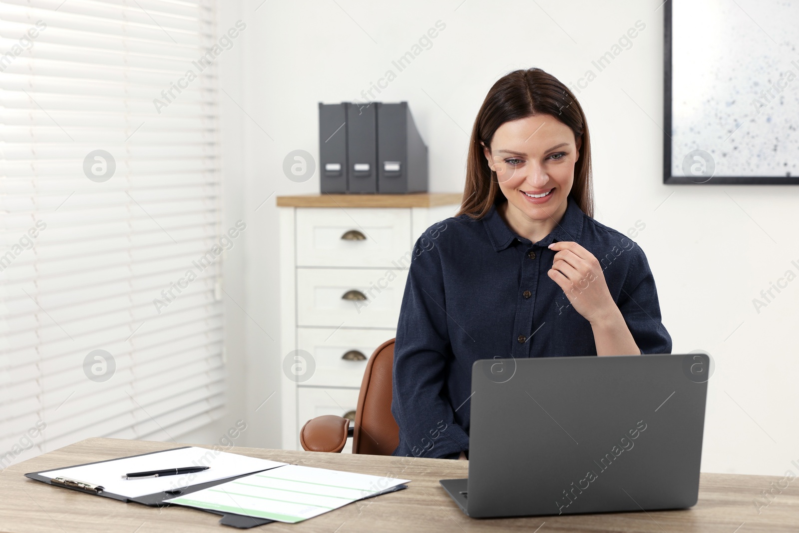 Photo of Woman having video chat via laptop at wooden table in office, space for text