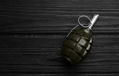 Photo of Hand grenade on black wooden table, top view. Space for text