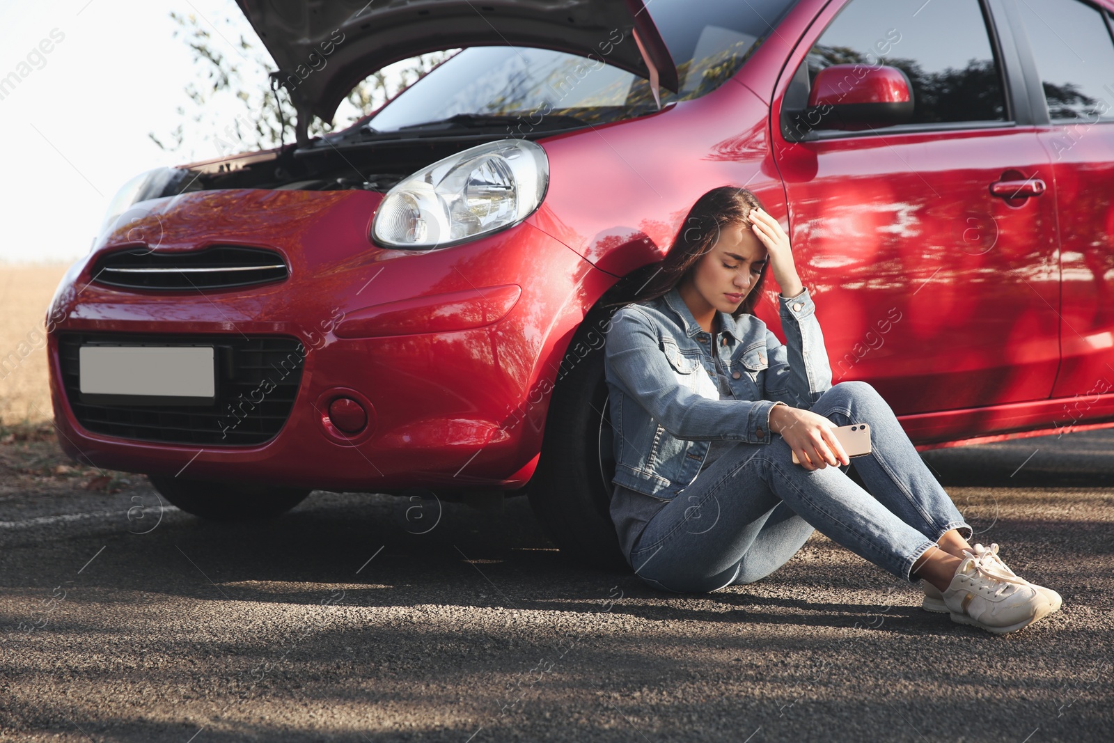 Photo of Stressed woman with smartphone near broken car outdoors
