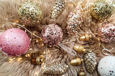 Photo of Beautiful Christmas tree baubles and fairy lights on faux fur, above view