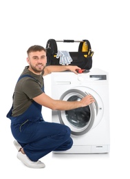 Plumber fixing washing machine on white background