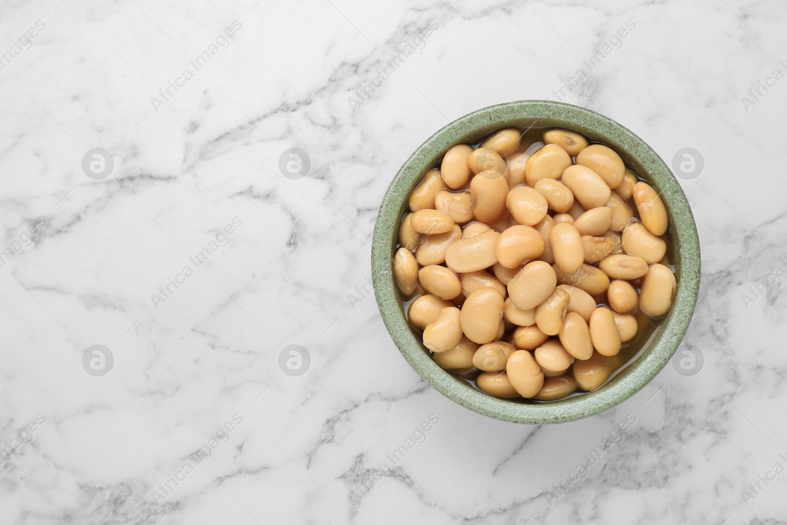 Photo of Bowl of canned kidney beans on white marble table, top view. Space for text