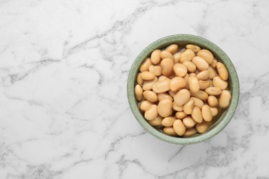 Photo of Bowl of canned kidney beans on white marble table, top view. Space for text