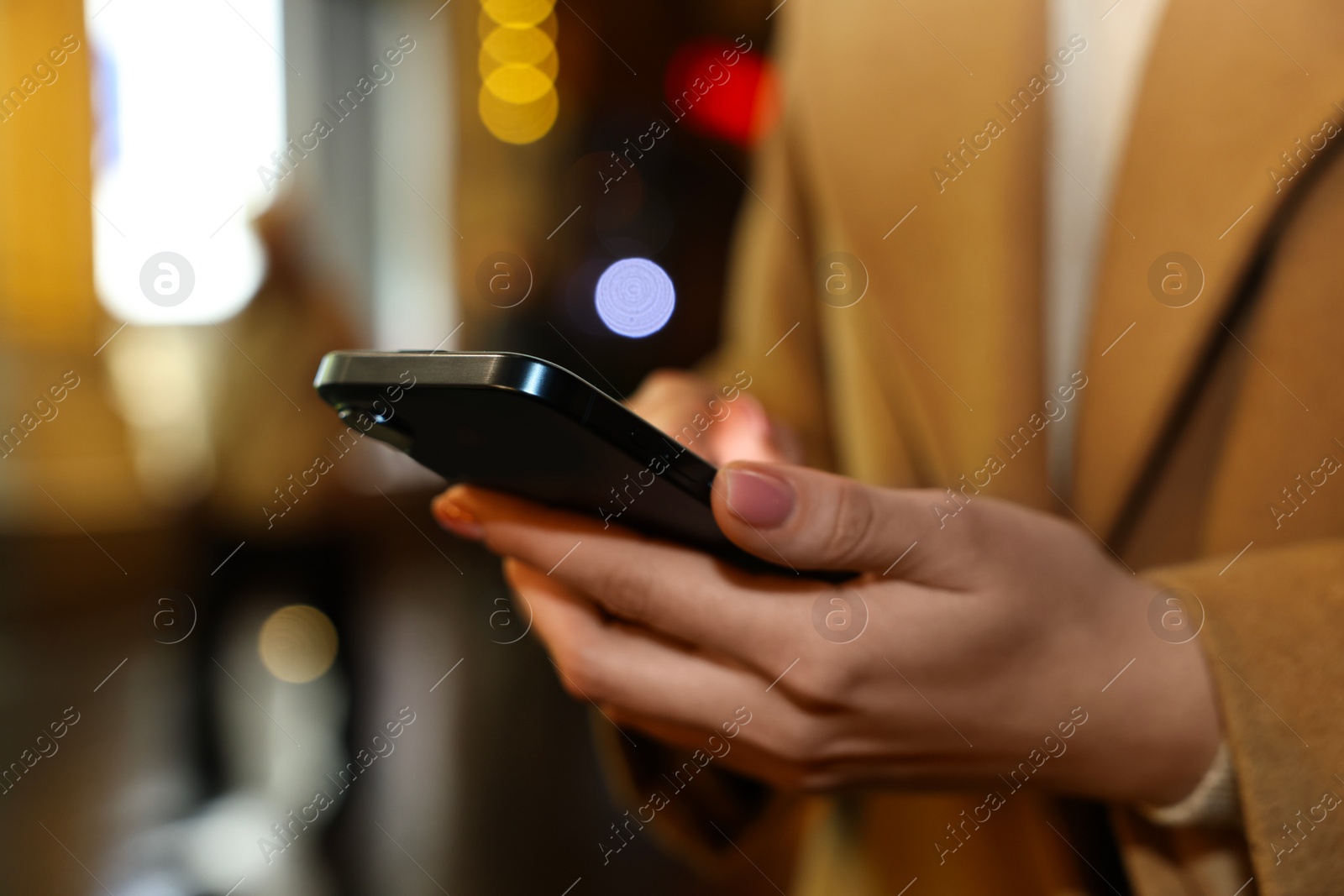 Photo of Woman with smartphone on night city street, closeup