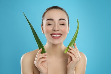 Photo of Young woman with aloe vera leaves on light blue background