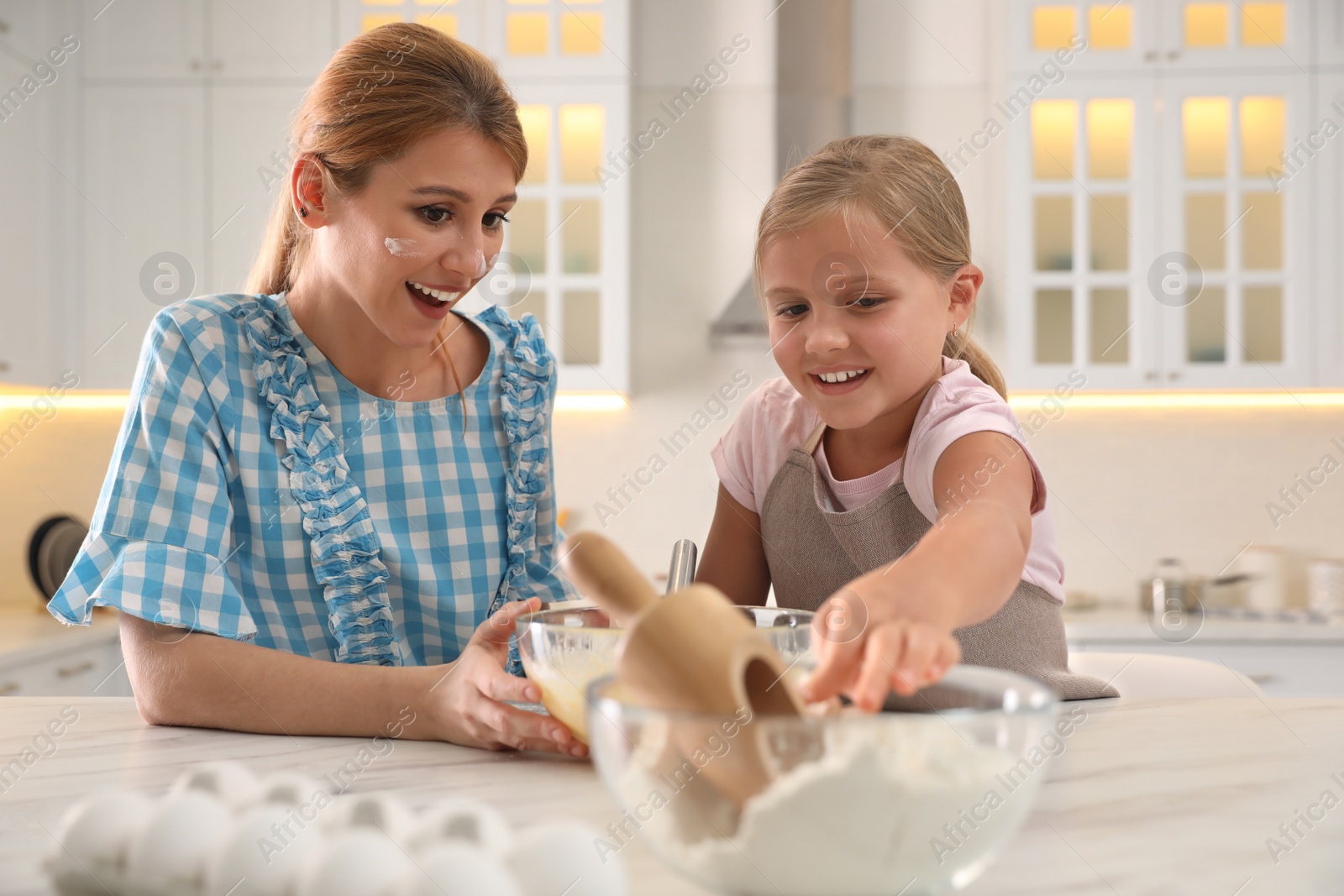 Photo of Mother and daughter making dough together in kitchen