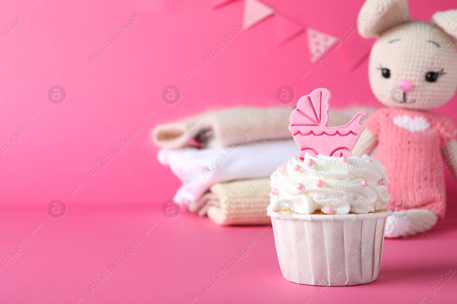 Photo of Beautifully decorated baby shower cupcake with cream and girl topper on pink background. Space for text