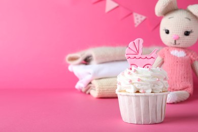 Beautifully decorated baby shower cupcake with cream and girl topper on pink background. Space for text