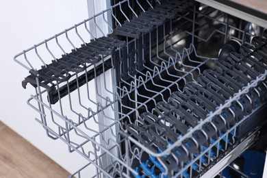 Photo of Open clean empty dishwasher indoors, closeup. Home appliance