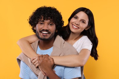 International dating. Happy couple hugging on yellow background