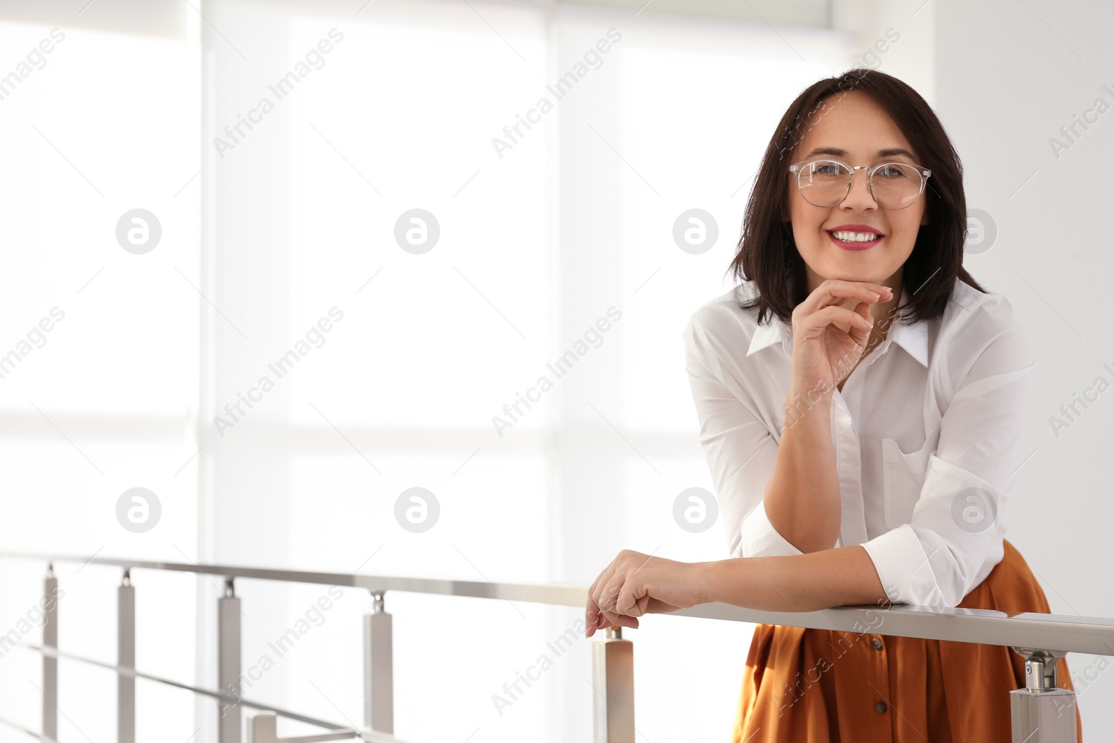 Photo of Happy mature businesswoman leaning on railing in office. Space for text