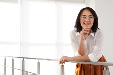 Photo of Happy mature businesswoman leaning on railing in office. Space for text