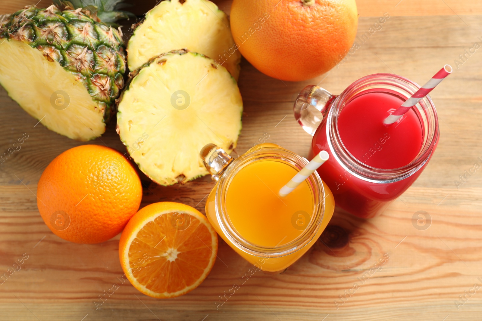 Photo of Flat lay composition with different juices in mason jars and fresh fruits on wooden table