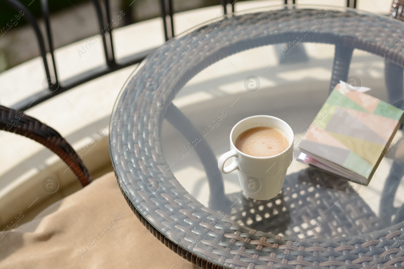 Photo of Ceramic cup of drink and notebook with pen on glass table outdoors. Good morning
