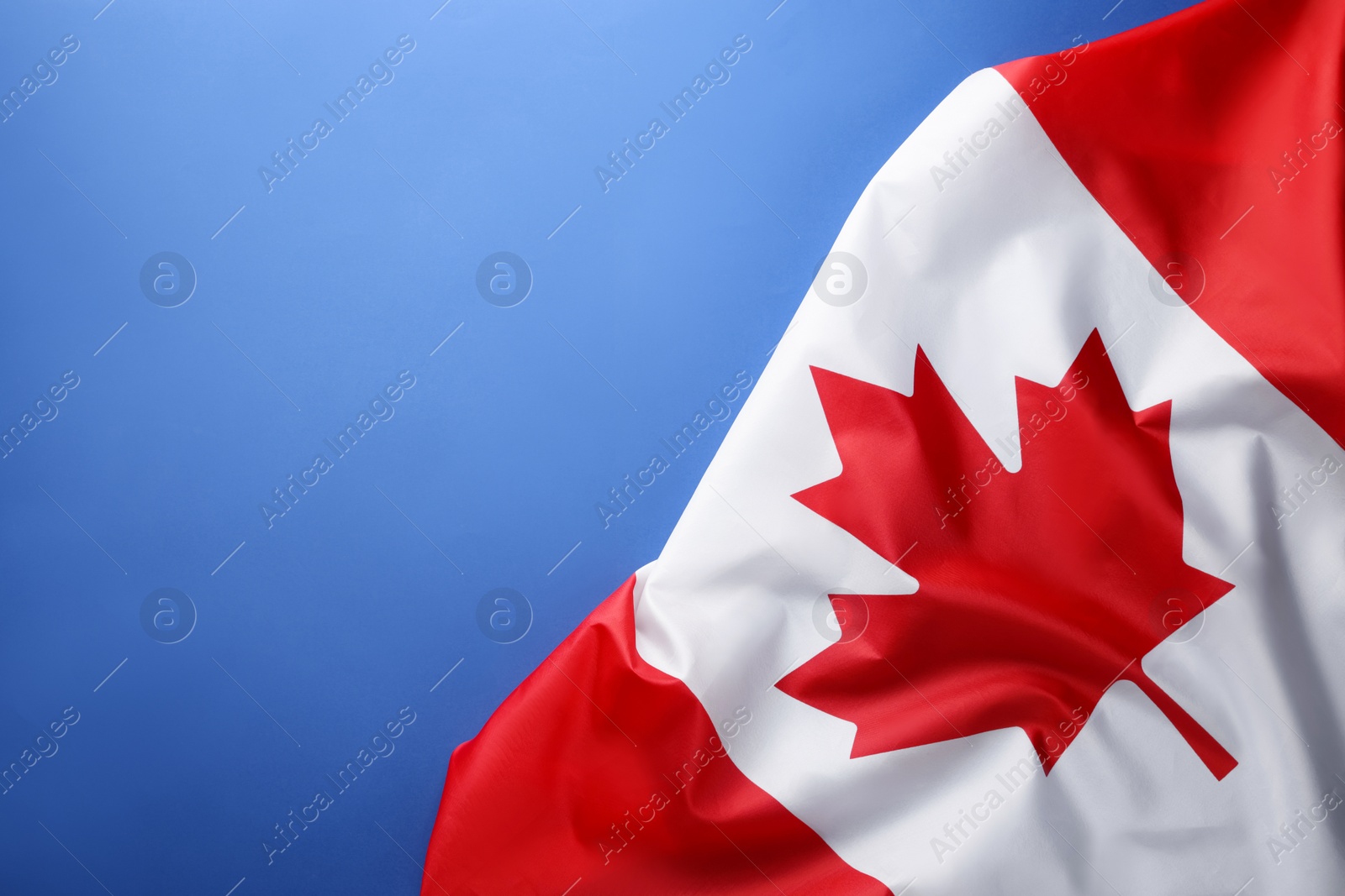 Photo of Flag of Canada on blue background, top view. Space for text