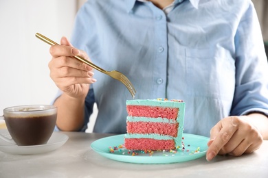 Woman eating fresh delicious birthday cake at table, closeup