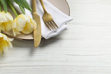 Stylish table setting with cutlery and tulips on white wooden background. Space for text