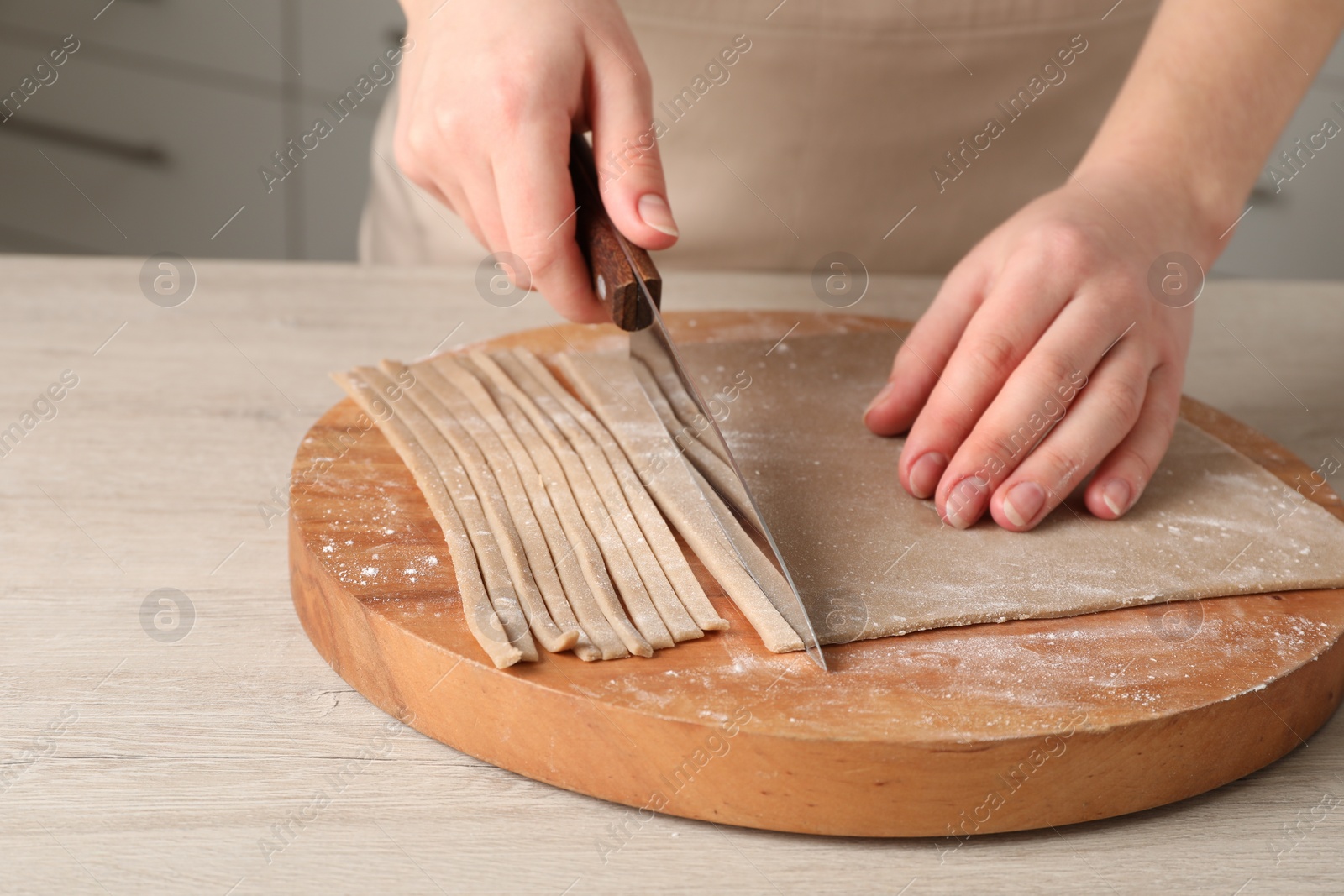 Photo of Woman making soba (buckwheat noodles) at wooden table, closeup