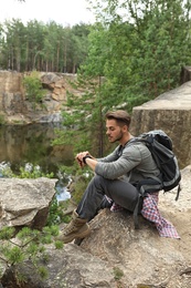 Young man on rocky mountain near lake. Camping season