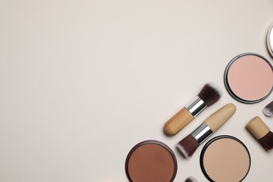 Photo of Different face powders and makeup brushes on beige background, flat lay. Space for text