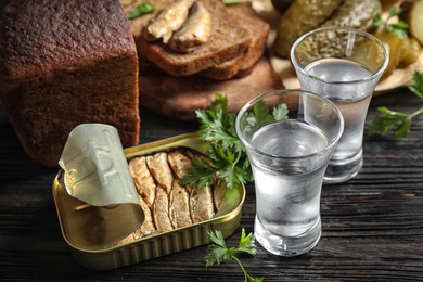 Photo of Cold Russian vodka with snacks on black wooden table, closeup