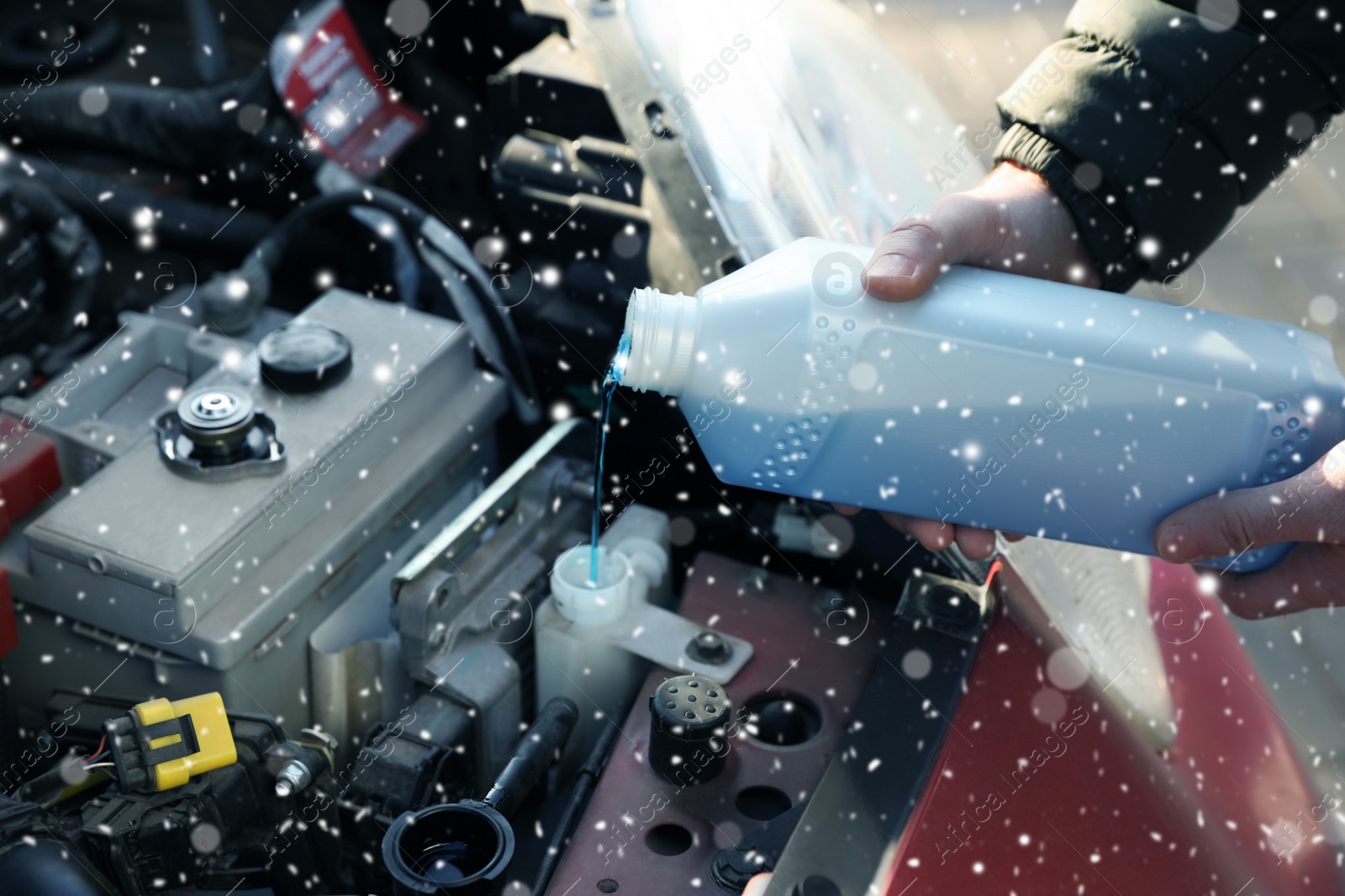 Image of Man filling car radiator with antifreeze outdoors, closeup