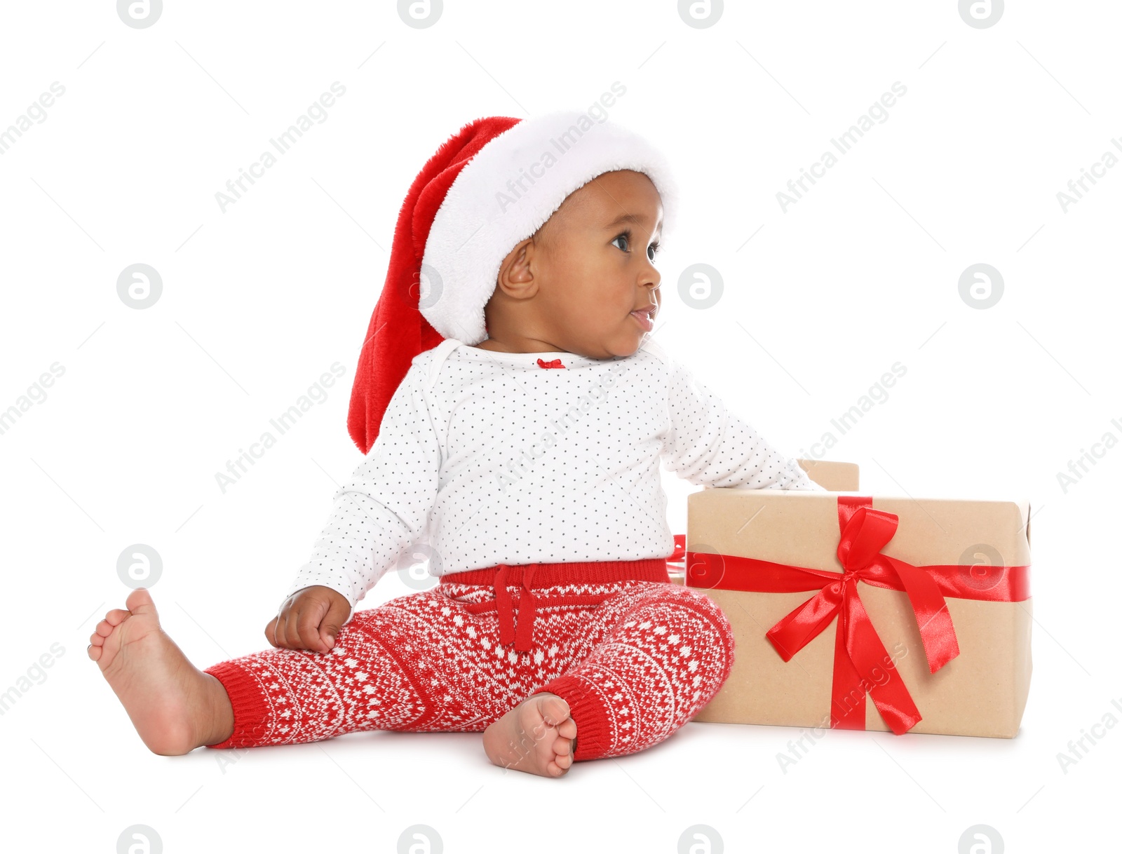 Photo of Festively dressed African-American baby with Christmas gifts on white background