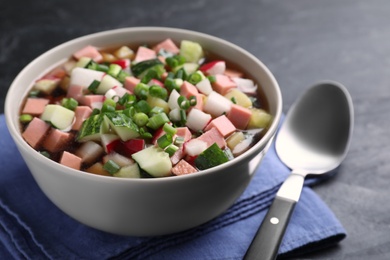 Photo of Delicious cold okroshka with kvass served on black table, closeup. Traditional Russian summer soup