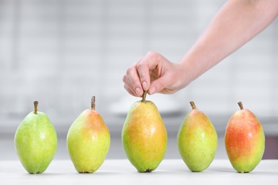 Photo of Woman taking fresh ripe pear from table in kitchen, closeup