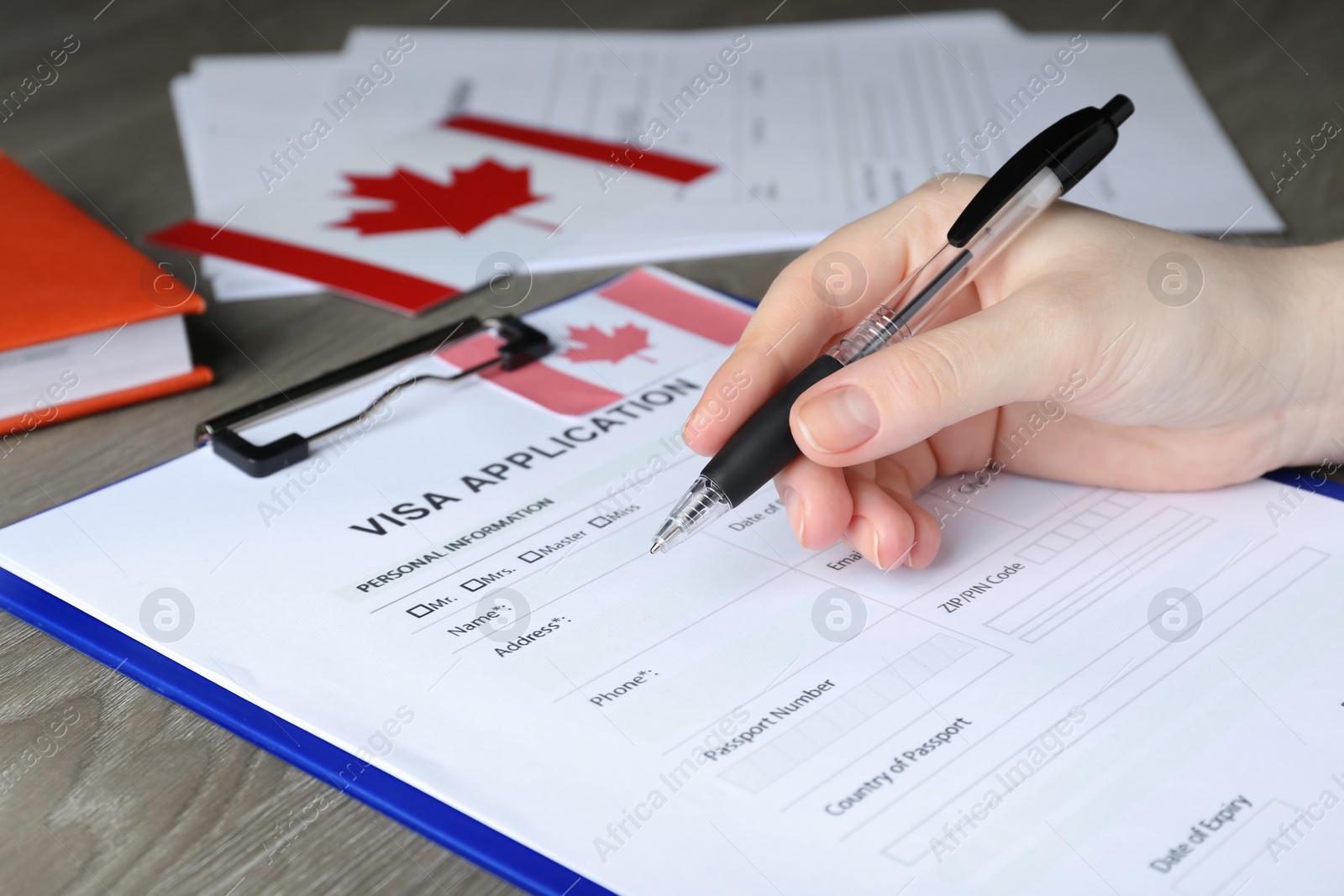 Photo of Woman filling visa application form to Canada at table, closeup
