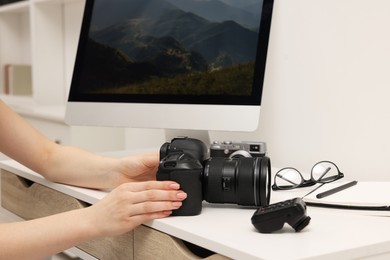 Photographer with camera at white table indoors, closeup