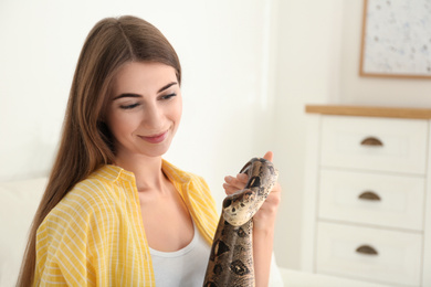 Young woman with boa constrictor at home. Exotic pet