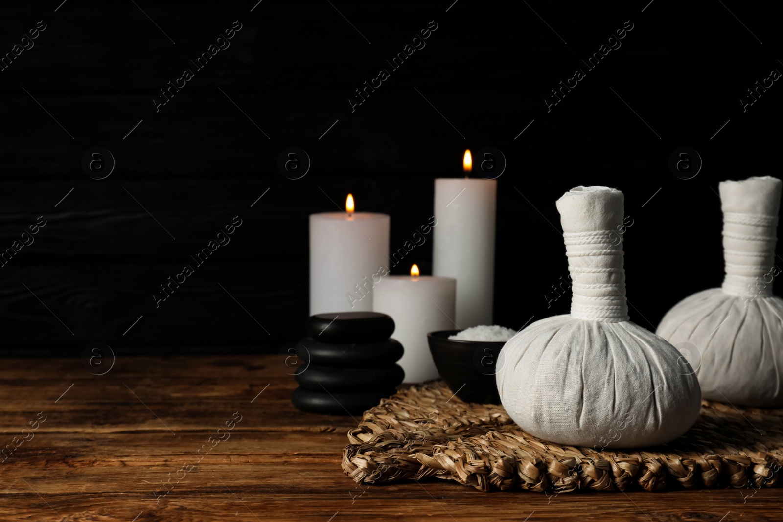 Photo of Herbal massage bags other spa products on wooden table, space for text