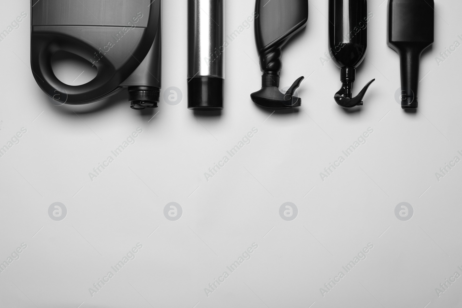 Photo of Black bottles and canister on white background, flat lay. Space for text