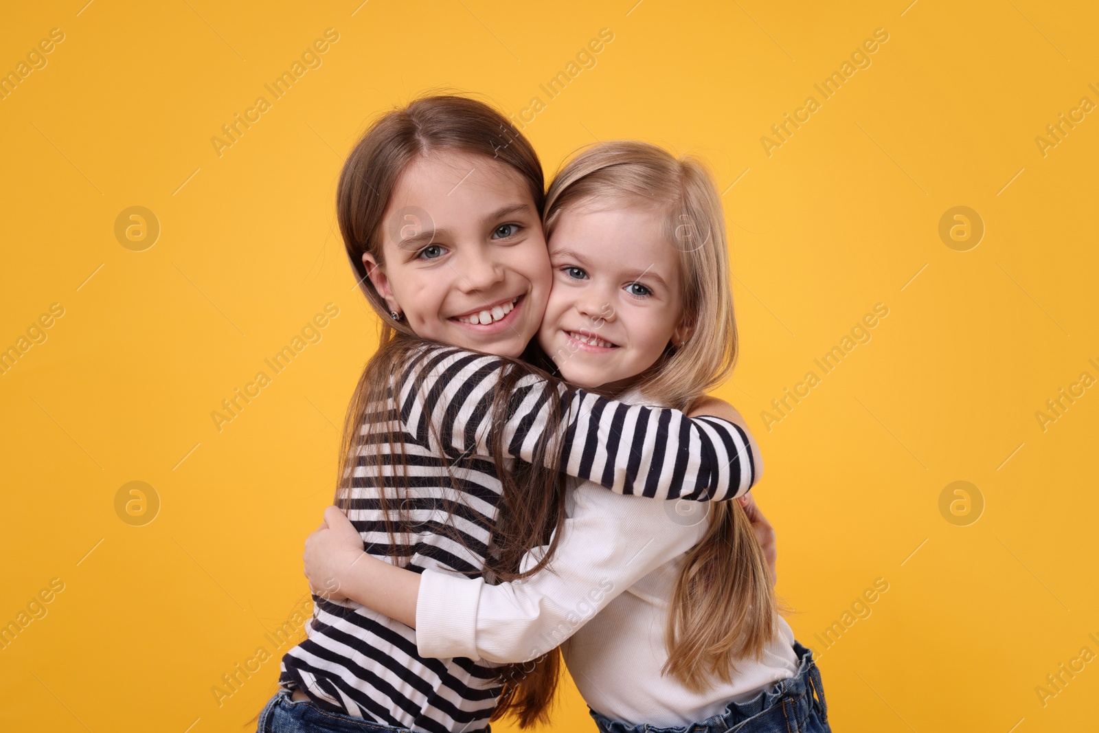 Photo of Portrait of cute little sisters on orange background