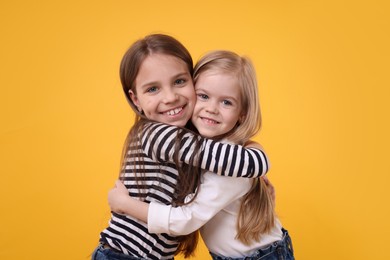 Photo of Portrait of cute little sisters on orange background